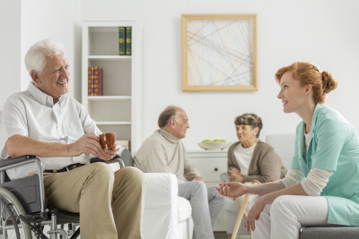 Elderly patients in nursing home talking with young nurse